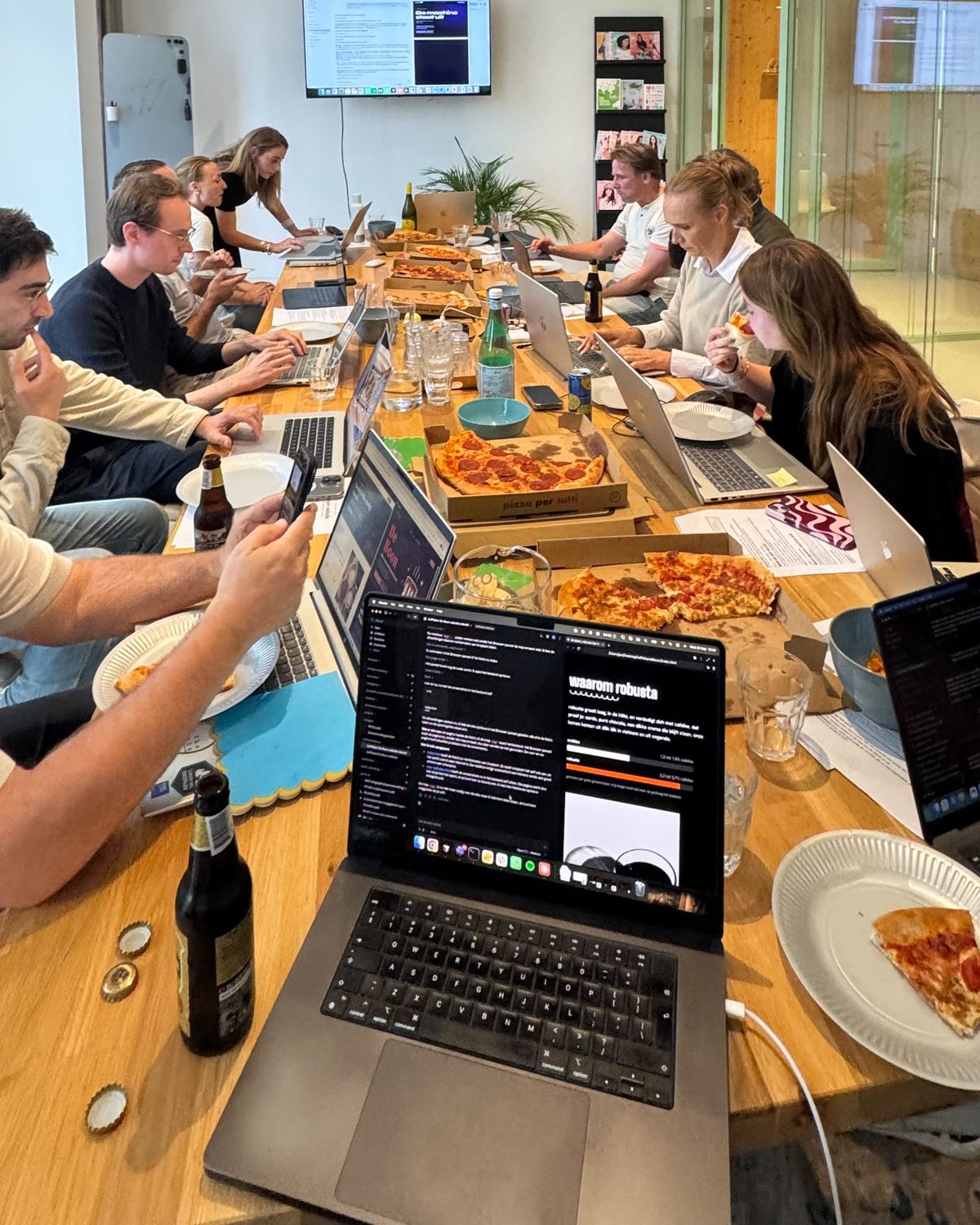 Deelnemers bouwen met Claude Code, laptops en pizza op tafel